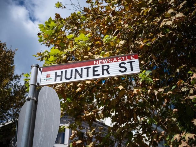 Hunter Street street sign in Newcastle against a blue sky and leaves